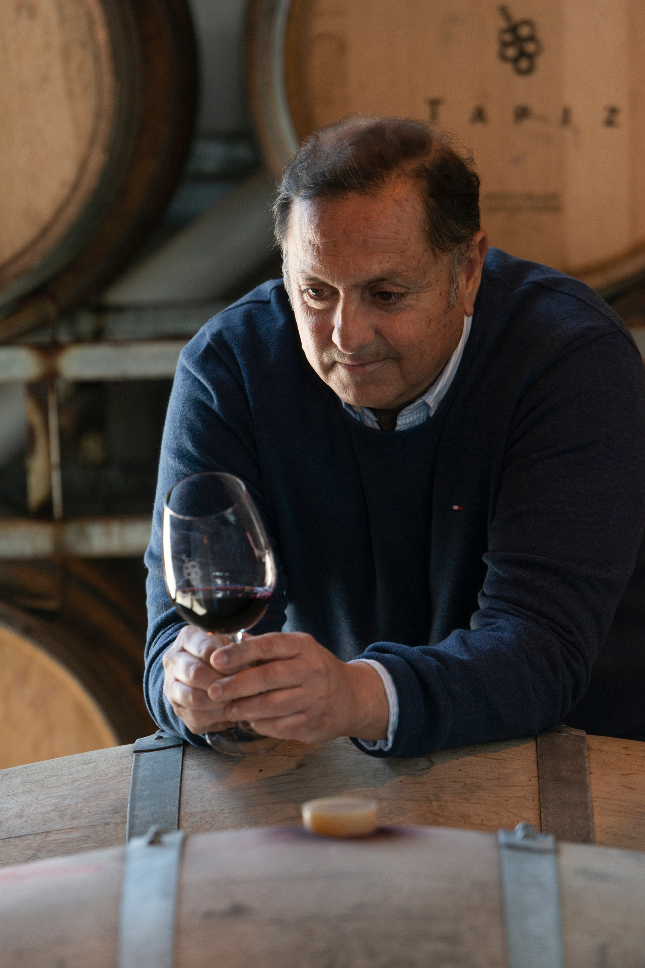 Winemaker in cellar examining wine